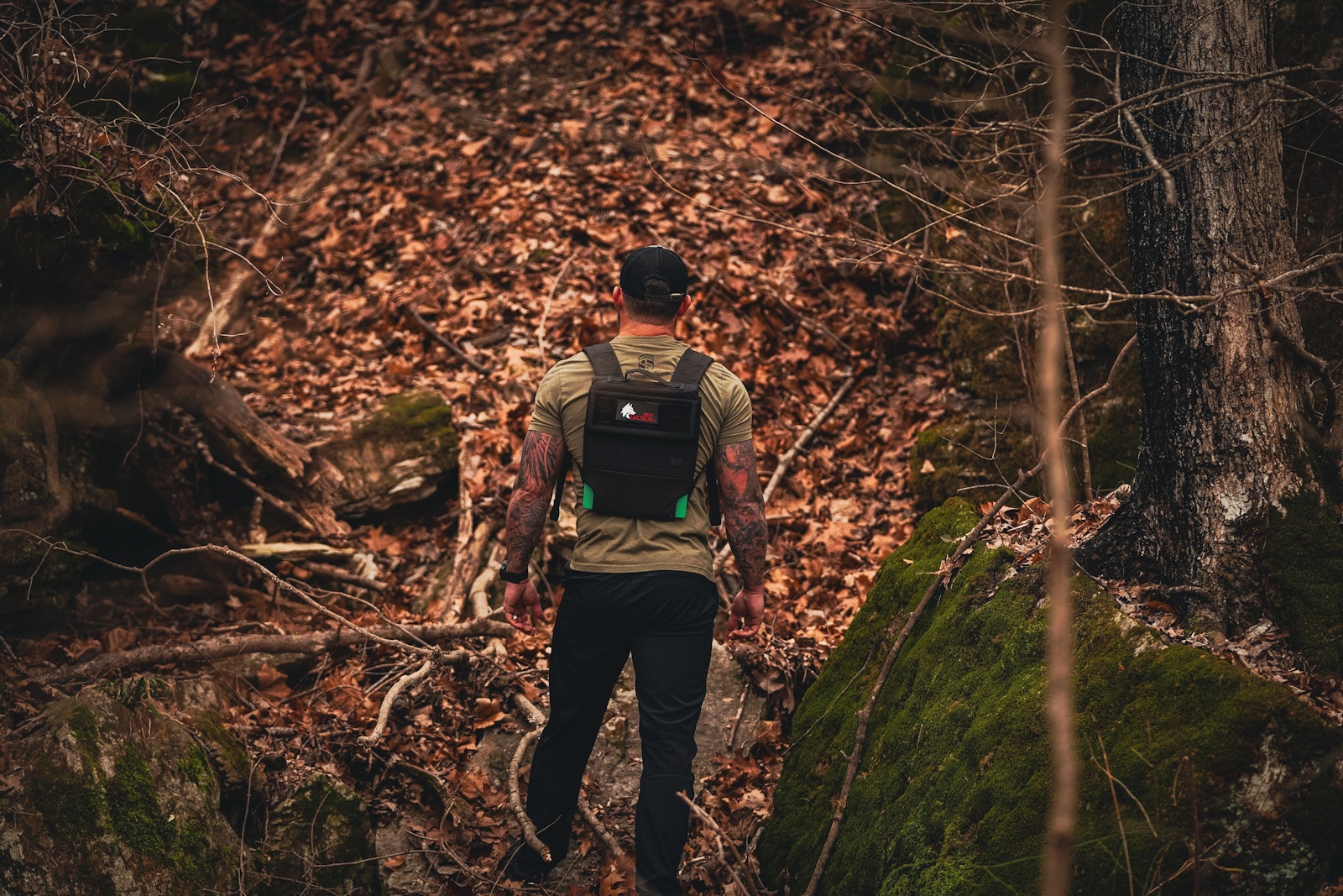 Man walking a gravel trail into the woods wearing a Wolf plate carrier