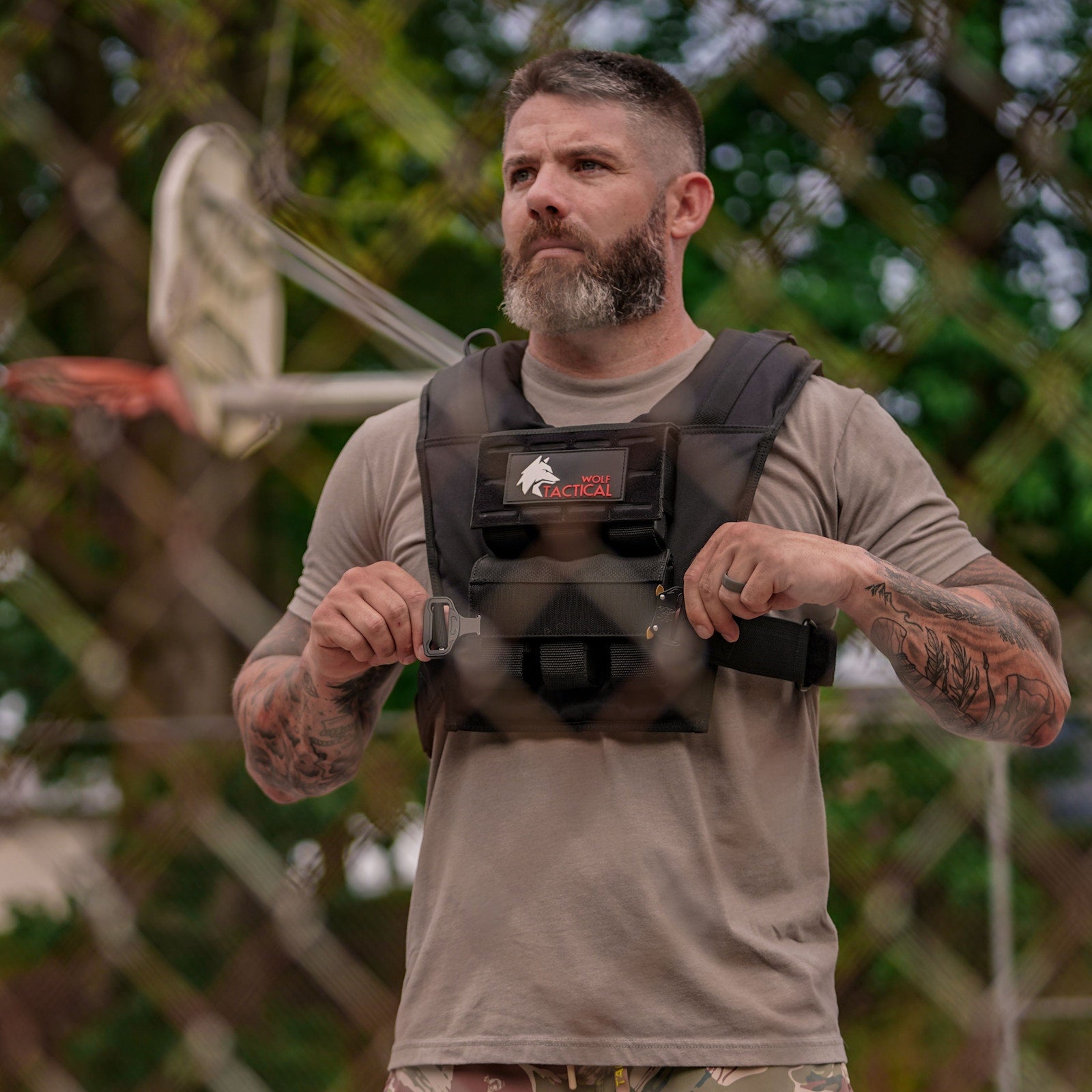 Man adjusting the straps of a Wolf weighted training vest in a park